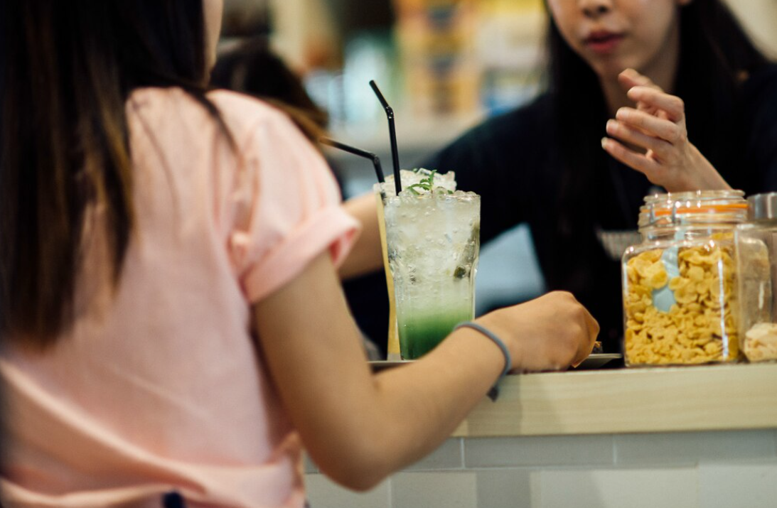 飲料店面設計情境,顧客在吧台座位區享用冰飲並進行交流